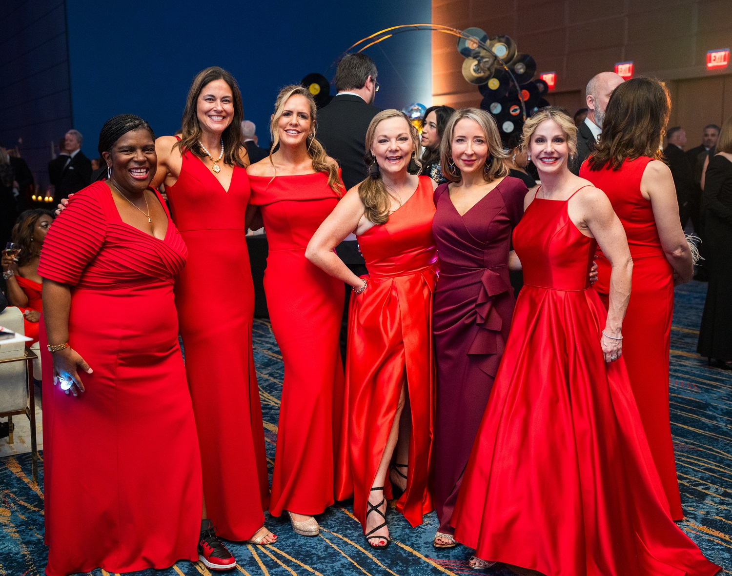 Group of seven women in red dresses.